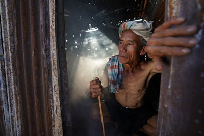 Shirtless senior man holding stick