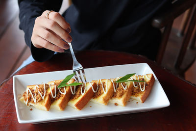 Close-up of hand holding food in plate