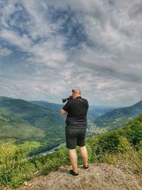 Rear view of man photographing against sky