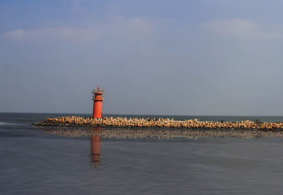 Lighthouse by sea against sky