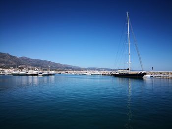 Sailboats in sea against clear blue sky