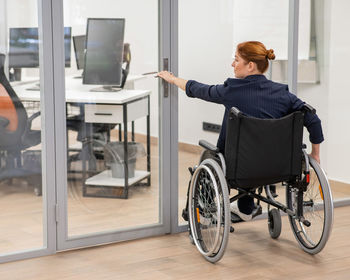 Side view of man using mobile phone while sitting on wheelchair