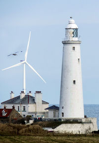 Lighthouse by sea against clear sky