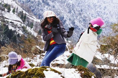 Mother and daughters playing with snow against mountains