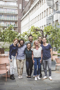 Full length portrait of smiling colleagues standing in office yard