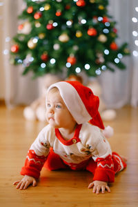 Cute girl with christmas tree on floor at home