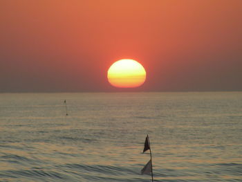 Silhouette person on sea against sky during sunset