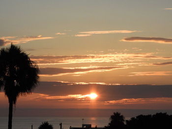 Silhouette trees by sea against romantic sky at sunset