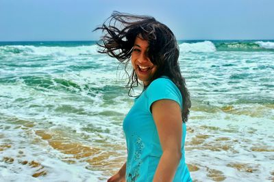 Portrait of smiling young woman standing on sea shore