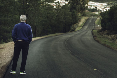 Rear view of man standing on road 