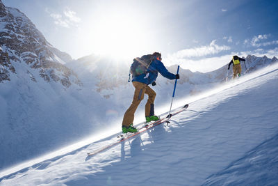 Man ski touring up hill in the wind and backlit by the sun