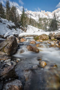 Surface level of stream amidst rocks against sky