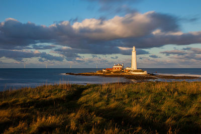 Lighthouse by sea against sky