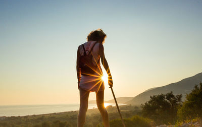 Rear view of woman standing at sunset