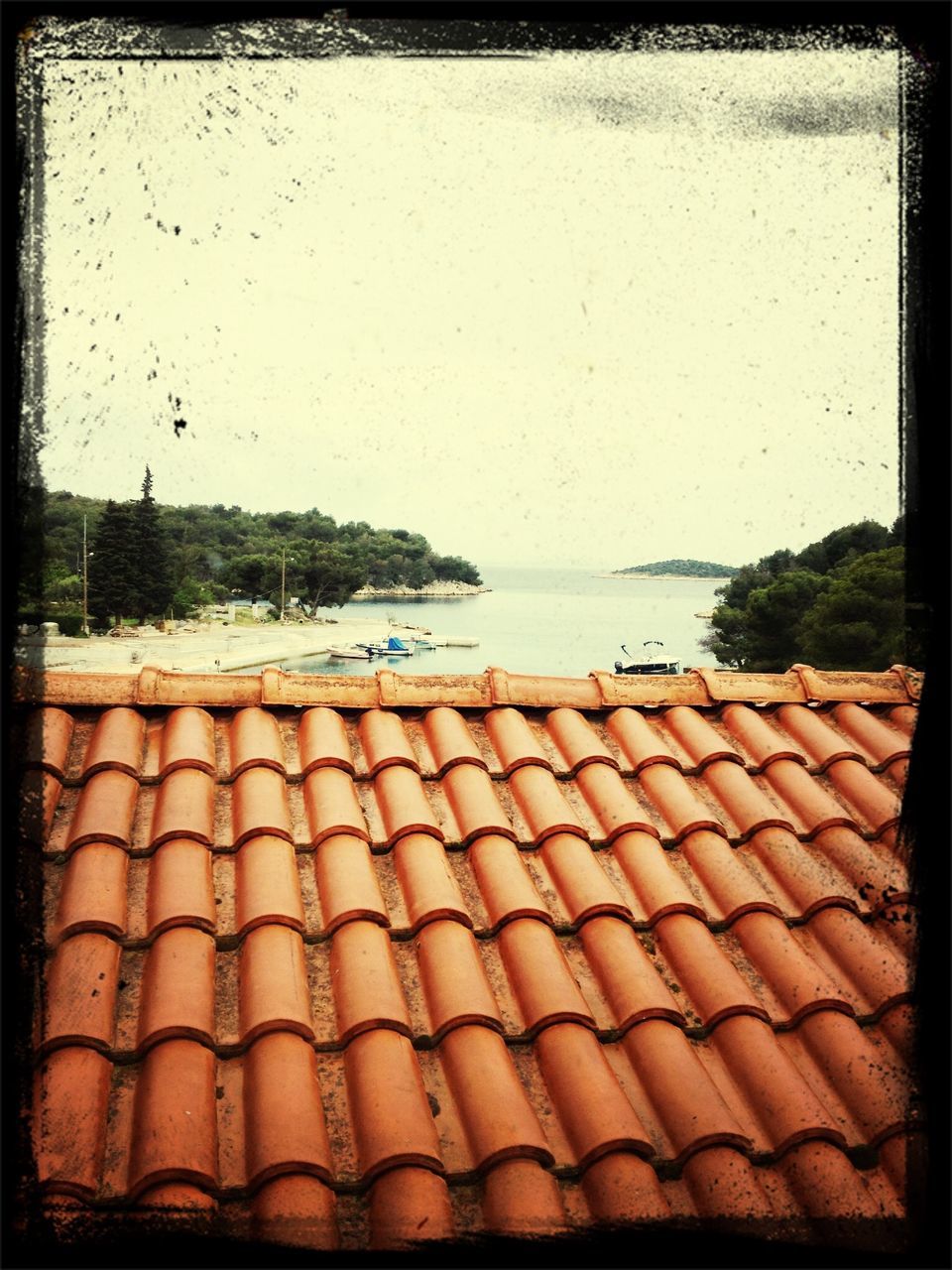 transfer print, auto post production filter, roof, sky, water, sea, built structure, outdoors, day, nature, building exterior, no people, tranquility, tree, architecture, horizon over water, high angle view, beach, wood - material, house