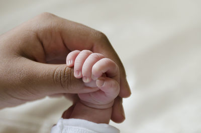 Close-up of cropped woman holding newborn baby hand