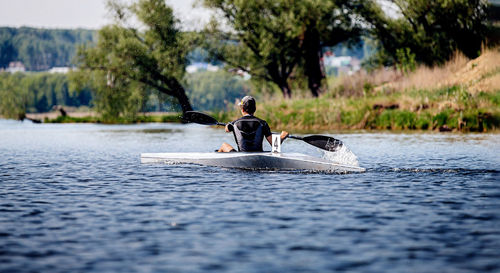 Rear view of man kayaking on lake