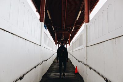 Rear view of man walking on corridor