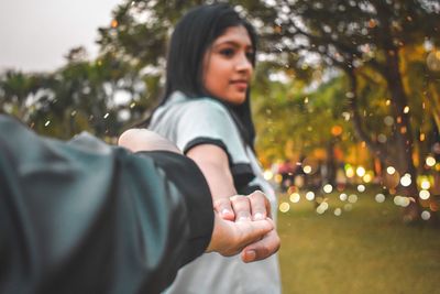 Cropped image of man holding woman hand in park
