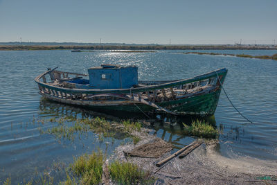 Abandoned boat moored in sea against clear sky