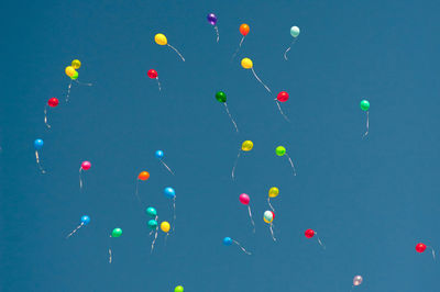 Low angle view of balloons flying against blue sky