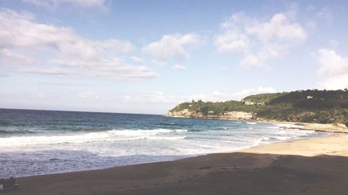 Scenic view of beach against cloudy sky