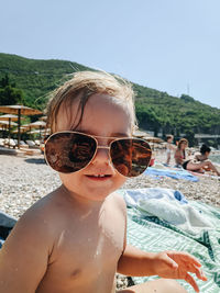 Portrait of shirtless wearing sunglasses on beach