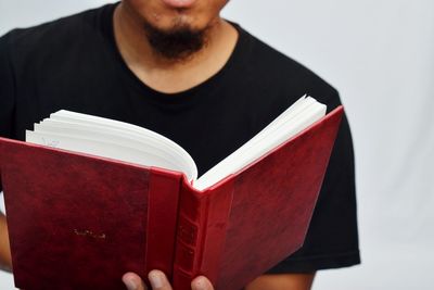 Midsection of man reading book against white background