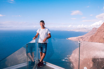 Side view of man standing by sea against sky