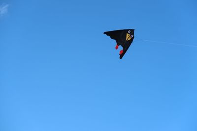 Low angle view of kite flying against clear blue sky