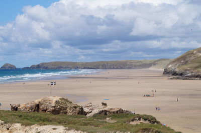 Group of people at beach against cloudy sky