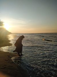 Muslim girl wearing burqa on the beach during sunset