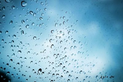 Full frame shot of wet window against blue sky