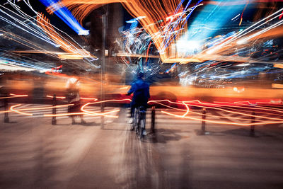 Blurred motion of man walking on illuminated street at night
