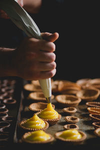 Cropped hand of chef making pastries with piping bag in bakery