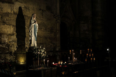 Statue against illuminated building at night