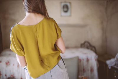 Rear view of woman standing against yellow building