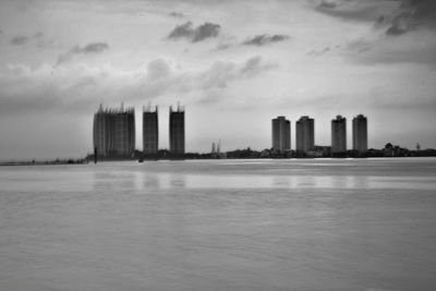 Modern buildings by sea against sky in city