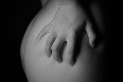 Close-up of woman touching hand against black background