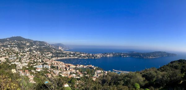 Panoramic view of city by sea against blue sky