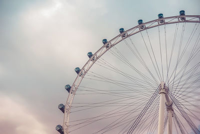 Low angle view of ferris wheel against cloudy sky