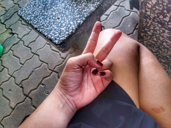 Close-up of hand gesturing on thigh while sitting on footpath