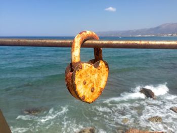 Close-up of padlocks on metal chain against sky