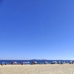 Crowd on beach against clear blue sky