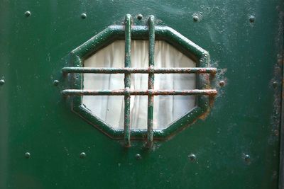 Fishing house door in nautical style, in rusty metal green, with small window, genoa, liguria, italy