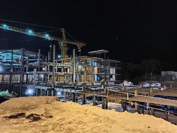 Illuminated construction site against sky at night