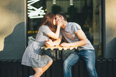 Young couple kissing while sitting at sidewalk cafe