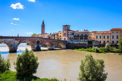 Arch bridge over river against buildings