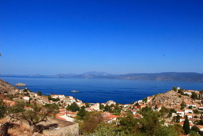 High angle view of town by sea against blue sky