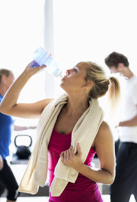 Fit young woman drinking water at health club